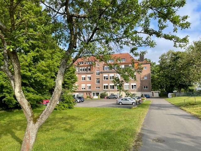 Haus Nettetal ist ein mehrstöckiges rot geklinkertes Haus mit Bäumen und Rasen davor