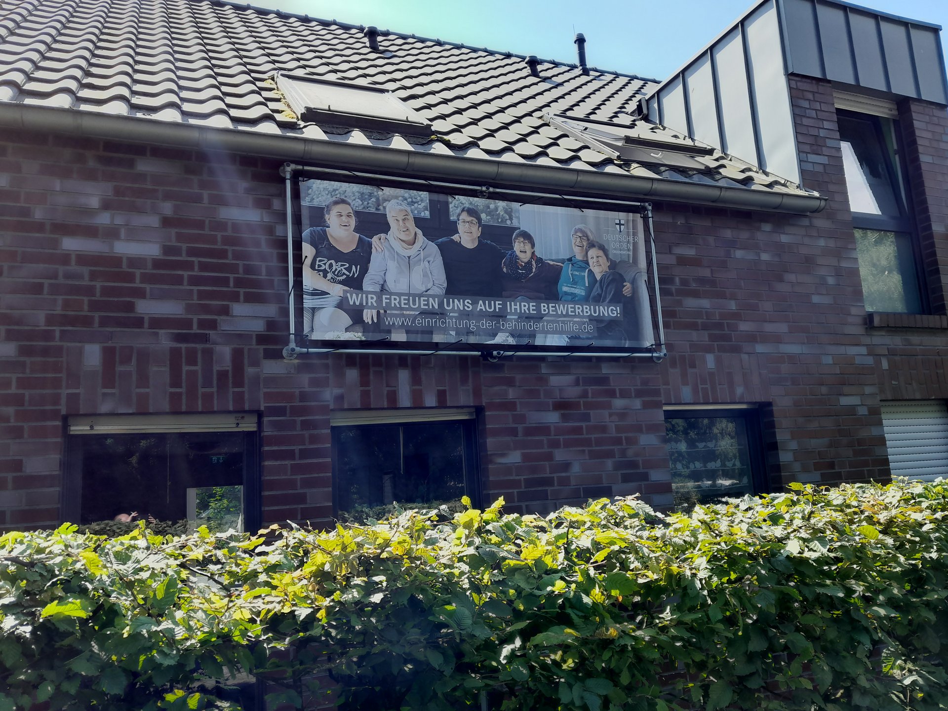 rot geklinkerte Fassade der Behindertenhilfe Haus Nettetal mit grüner Hecke davor